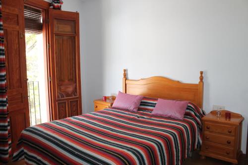 a bedroom with a bed with a striped blanket and a window at Apartamento Rurales Rosendo: Poleo Menta in Capileira