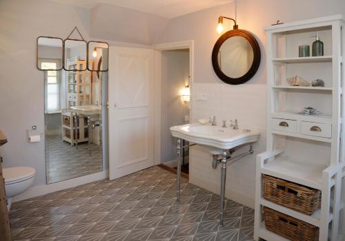 a white bathroom with a sink and a mirror at Domaine du Plessis in Le Plessis-Luzarches