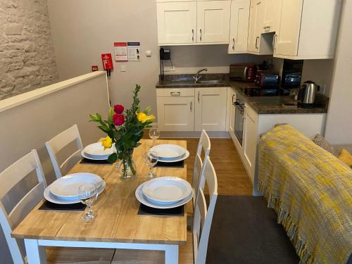 una mesa de comedor con platos y flores. en Brampton Holiday Homes - The Mews Apartment en Brampton