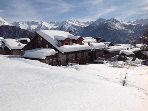 a house covered in snow with mountains in the background at Agriturismo il Fiocco in Cesana Torinese