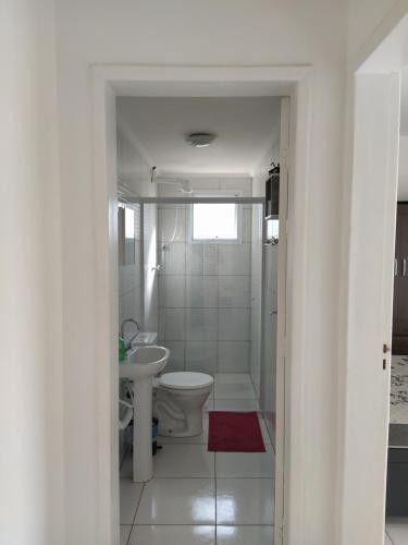 a white bathroom with a toilet and a sink at Caraguatatuba de frente para o mar in Caraguatatuba