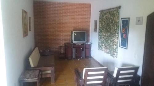 een kamer met stoelen en een tv en een bakstenen muur bij Chácara Santista in Serra Negra