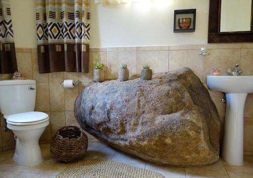 ein Badezimmer mit einer großen, felsförmigen Badewanne in der Ecke in der Unterkunft Vekis Village in Mbabane