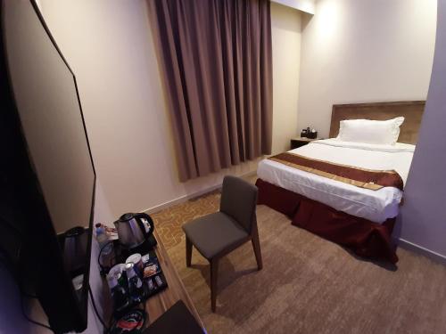 a hotel room with a bed and a chair at Qasr Alshamal Hotel in Arar