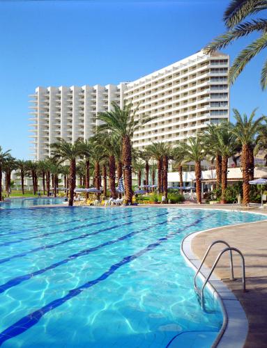 a large pool with palm trees and a hotel at David Dead Sea Resort & Spa in Ein Bokek