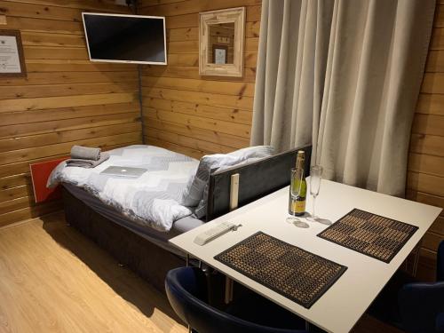 um quarto com uma cama e uma mesa com uma garrafa de vinho em Southernwood - Garden Lodge 7 em Didcot