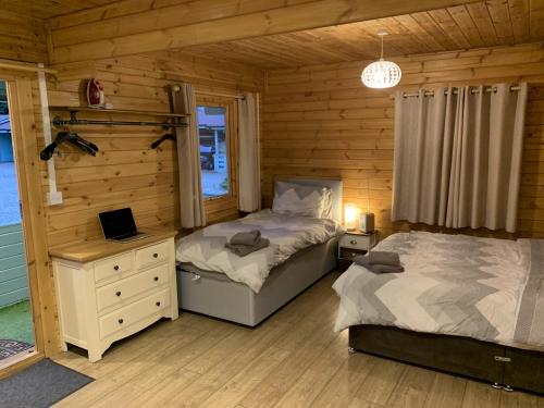 1 Schlafzimmer mit 2 Betten in einem Blockhaus in der Unterkunft Southernwood - Garden Lodge 8 in Didcot