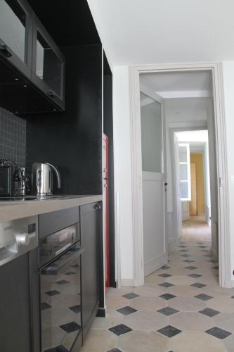 a kitchen with a refrigerator and a tile floor at Domaine du Plessis in Le Plessis-Luzarches