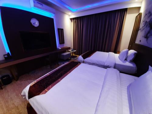 a hotel room with two beds and a flat screen tv at Qasr Alshamal Hotel in Arar