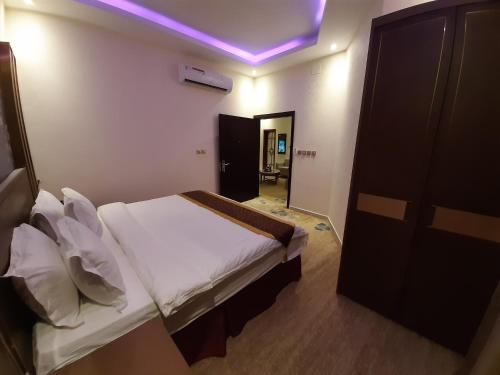 a bedroom with a bed and a purple light at Qasr Alshamal Hotel in Arar
