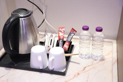 a counter with a coffee pot and two bottles of water at Qasr Alshamal Hotel in Arar