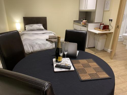 Camera con un tavolo, una bottiglia di vino e un letto di Southernwood - Garden Lodge 12 a Didcot