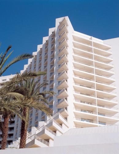 a white building with a palm tree in front of it at David Dead Sea Resort & Spa in Ein Bokek