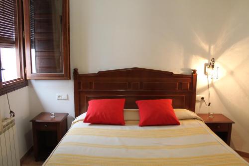 a bedroom with a bed with two red pillows at Apartamentos Rurales Rosendo: La Orquídea in Capileira