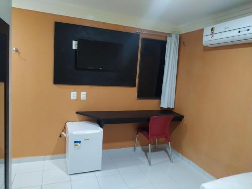 cocina con escritorio y silla roja en una habitación en Hotel Executivo Boulevard, en Mossoró