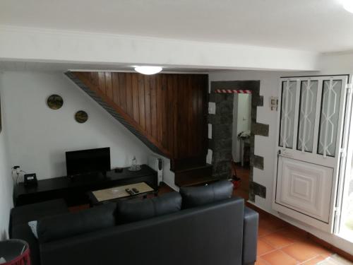 een woonkamer met een zwarte bank en een trap bij Casa Dos Mosteiros in Mosteiros