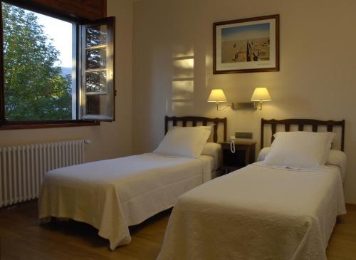 two beds in a hotel room with a window at Hotel Celisol Cerdagne in Bourg-Madame