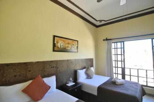 Hotel Rinconada del Convento في إسامال: غرفة نوم بسريرين ونافذة