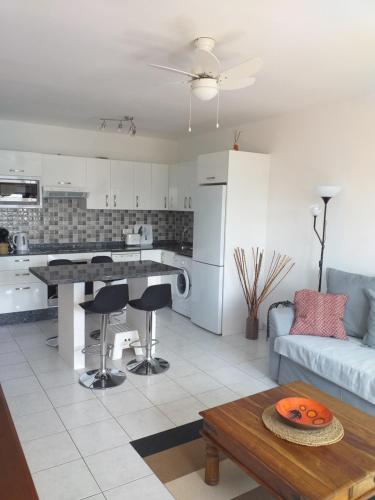 Una cocina y una sala de estar con un sofá y una mesa. en Bungalow Playa Bastian - Piscina climatizada - Wifi - Playa 1 min., en Costa Teguise
