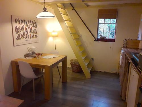 a dining room with a table and a staircase at Het Vogelhuisje in Twijzelerheide