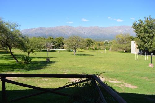 a field with a fence and a soccer field with mountains at Cabañas Tintihuasi in Villa de Las Rosas