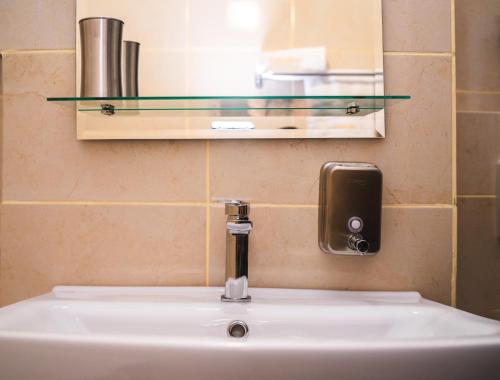 a bathroom sink with a soap dispenser and a mirror at Hideout Apartment in Predeal