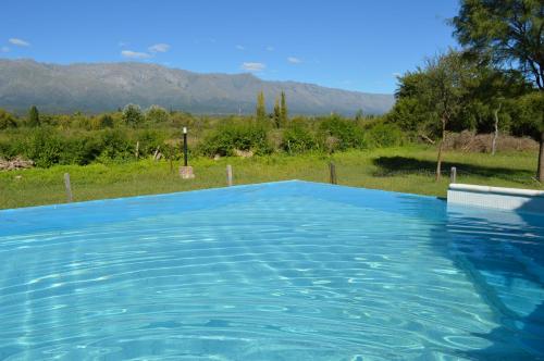 a blue swimming pool with mountains in the background at Cabañas Tintihuasi in Villa de Las Rosas