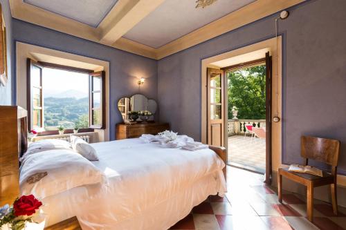 a bedroom with a large bed and a large window at VILLA TURRI - Luxury Country & Padel Resort in Camporgiano