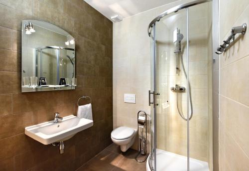 een badkamer met een wastafel, een toilet en een douche bij Hotel Pelikán in Lučenec