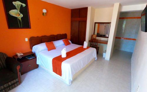 a bedroom with a large bed with orange walls at Hotel Uxulkah in Campeche