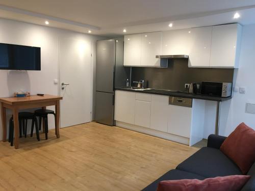 a living room with a table and a kitchen at Cosy flat in the quiet area with own garden, free parking and direct public transport link to the centre in Vienna
