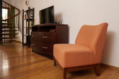 a living room with a chair and a tv at Sybaris Suites & Residences in Juan Dolio