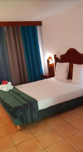 a bedroom with a large white bed with blue curtains at Appartement Mathena in Caritan