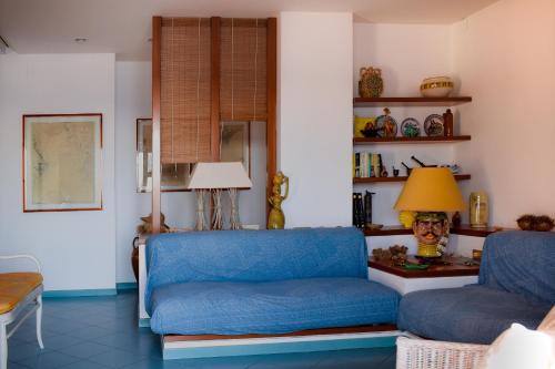 a living room with a blue couch and a lamp at Acitrezza View in Aci Castello
