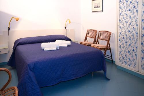 a bedroom with a blue bed with towels and two chairs at Acitrezza View in Aci Castello
