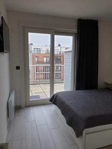 een slaapkamer met een bed en een groot raam bij Appartement, residentie Syci in Koksijde