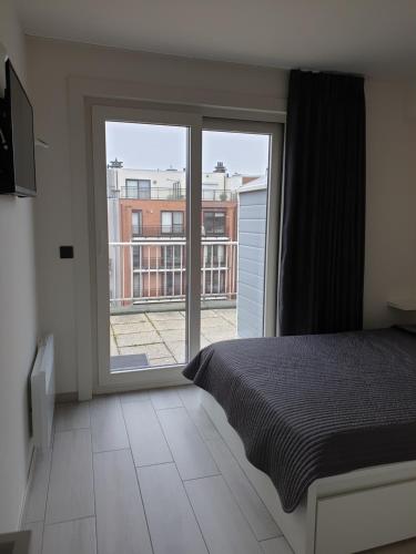 Un dormitorio con una cama y una ventana grande. en Appartement, residentie Syci, en Koksijde