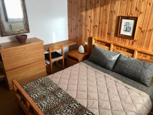 ein Schlafzimmer mit einem Bett mit einer Holzwand in der Unterkunft CinqueSensi - Condominio La Zoca in Madesimo