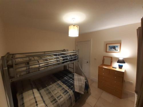 a bedroom with a bunk bed and a night stand at Beachside Holiday Home in Portrush