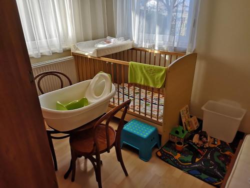 a baby crib with a sink and chairs in a room at Atlantika Apartman in Balatonboglár