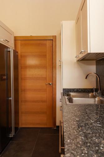 a kitchen with a wooden door and a sink at Sybaris Suites & Residences in Juan Dolio