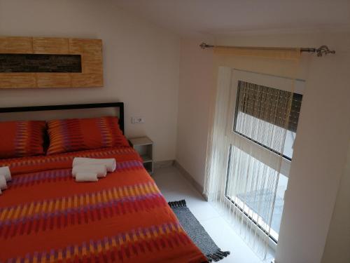 a bedroom with a bed with colorful pillows and a window at Vila Violeta in Šabac