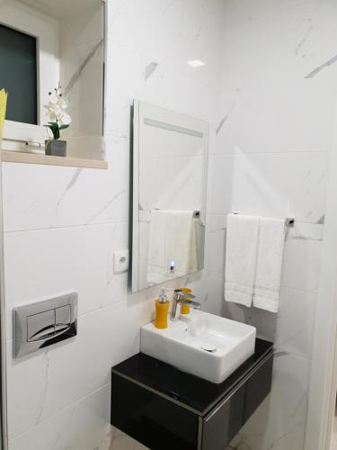 a white bathroom with a sink and a mirror at Beco's House - Suits in Ílhavo