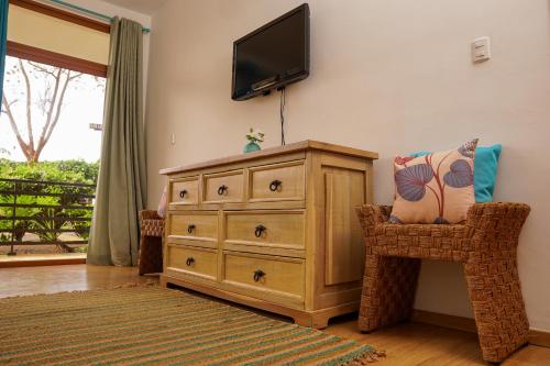 a room with a dresser and a television on a wall at Sybaris Suites & Residences in Juan Dolio