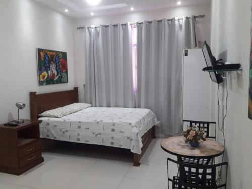 1 dormitorio con cama, mesa y TV en Studio Santa Clara, en Río de Janeiro