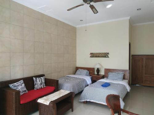 a room with two beds and a couch and a fan at Bali Reef Divers Tulamben in Tulamben