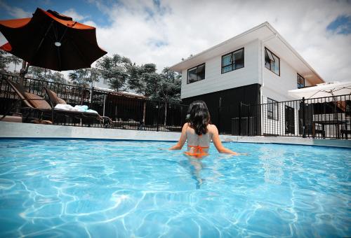 a woman in a swimming pool with an umbrella at Swimming Pool Holiday Villa in Auckland