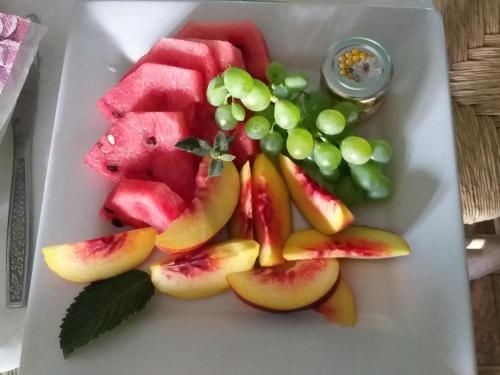 a white plate with fruit and grapes on it at Cabañas El Desván in Puente Negro