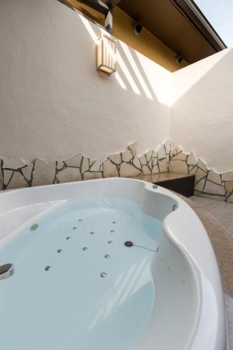 a bathtub in a bathroom with a stone wall at Tsuki no Yado Kaguya in Kawagoe