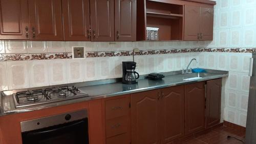 La cuisine est équipée de placards en bois et d'un four avec plaques de cuisson. dans l'établissement apartamento tejares de Salento, à Salento